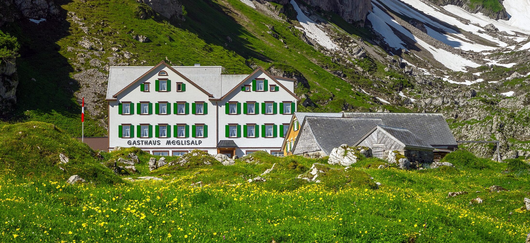 Hauptbild-2 Gasthaus Meglisalp mit blühender Alpwiese im Vordergrund